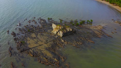 Drone-shot-turning-around-of-a-rock-front-of-a-tropical-beach-during-the-day