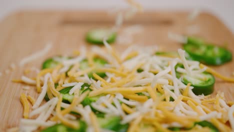 Shredded-cheese-falling-in-slow-motion-onto-a-pile-of-bright-green-sliced-jalapeños