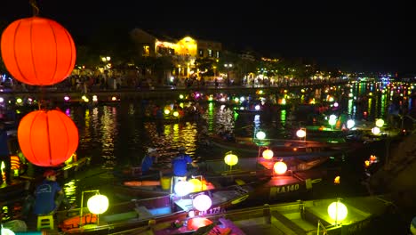 Static-shot-of-river-full-with-colourful-boats-and-Hoi-An-ancient-town-at-night-in-the-background
