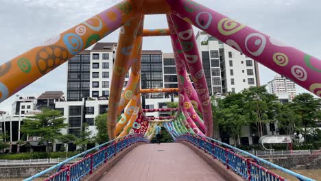 Man-walks-over-the-Alkaff-Bridge,-landmark-structure-on-the-Singapore-River,-Robertson-Quay,-Singapore