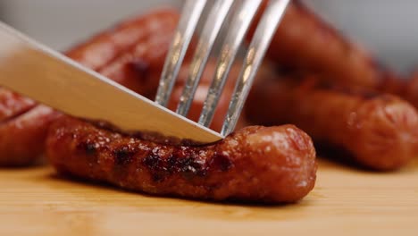 Fork-stabs-cooked-breakfast-sausage-and-dull-knife-tries-to-cut-through-on-cutting-board-in-slow-motion