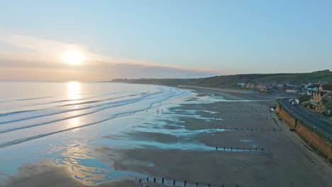 Sandsend,-Whitby,-North-Yorkshire-Coast-aerial-drone-movement-from-sea-towards-sea-and-dog-walkers