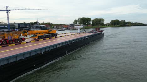 Aerial-View-Of-Dynamica-Barge-Carrying-Heavy-Goods-Vehicles-Along-Oude-Maas-Through-Zwijndrecht