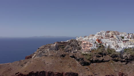 Aerial-panoramic-panning-view-of-Oia-in-Santorini,-Greece-with-clear-sky