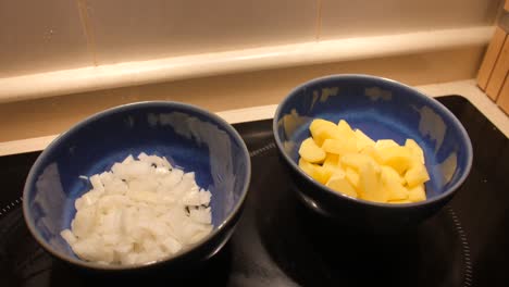 Detailed-close-up-of-diced-and-chopped-onions-and-potatoes-in-blue-bowl-ready-to-be-cooked-and-fried