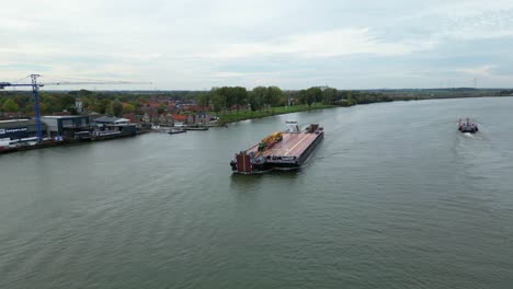 Aerial-View-Of-Dynamica-Barge-Carrying-Heavy-Goods-Vehicles-Along-Oude-Maas-Through-Zwijndrecht