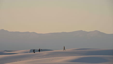 Telephoto-view-of-visitors-setting-up-sunset-picnic-on-White-Sands-dunes,-4K