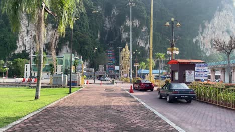 Cars-drive-towards-the-main-car-park-entrance-of-the-famous-Batu-Caves-Hindu-Temple-in-Selangor,-Kuala-Lumpur,-Malaysia