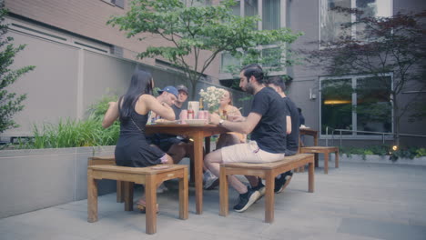 Group-Of-Millennial-Friends-Enjoying-Meal-In-Backyard-In-New-York