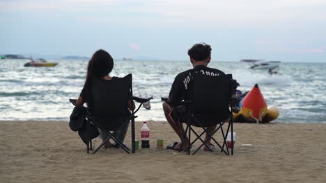 Couple-sitting-by-the-beach-and-enjoying-the-sea-view-in-Pattaya,-Thailand