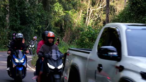 Feeding-on-the-right-side-of-the-jungle-road-while-park-visitors-drive-by-then-it-goes-inside-the-jungle,-Indian-Elephant-Elephas-maximus-indicus,-Thailand