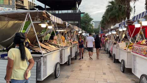 Tourists-walk-and-buy-food-at-an-outdoor-street-food-night-bazaar-in-Pattaya,-Thailand