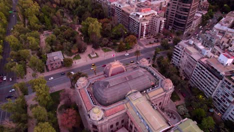 Chilean-National-Museum-of-Fine-Arts,-Aerial-Drone-Top-Notch-Fly-Above-Santiago-Chile,-Main-Road,-Downtown-with-Sunset-San-Cristobal-Hill-and-Urban-Park
