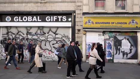 In-slow-motion-people-walk-past-empty-shop-spaces,-known-as-“dead-spaces”-on-Oxford-Street-during-the-day