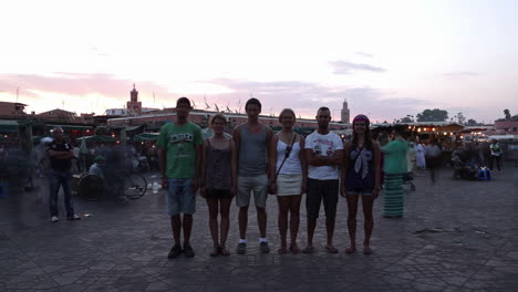 Group-Of-Tourists-Standing-For-Picture-Taking-At-The-Market-Square-In-Marrakesh,-Morocco-At-Sunset