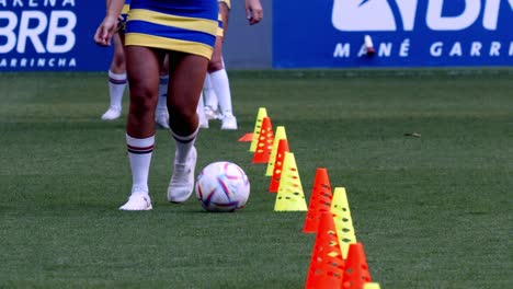 Female-footballer-dribbles-ball-around-cones,-slow-motion