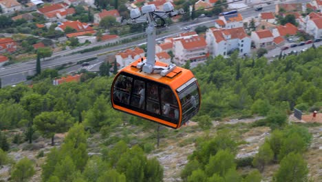 Orange-cable-car-descending-down-the-mountain-in-Dubrovnik,-Croatia