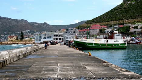 Tourists-standing-on-Kalk-Bay-stone-harbour-pathway-watching-Cape-Town-ocean-scenery