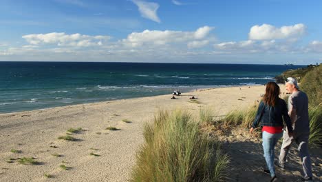 Paar-Zu-Fuß-Glücklich-In-Richtung-Sandstrand-Von-Hayle,-Um-Surfer,-Cornwall,-England-Zu-Beobachten