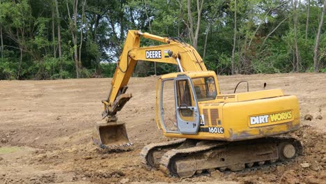 Deere-Hydraulic-excavator-tamping-dirt-on-the-bottom-of-pond-at-a-land-development-site