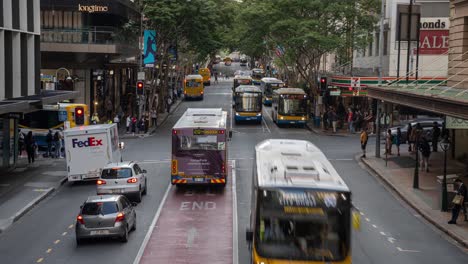 Brisbane-city-time-lapse-shot-of-busy-road-traffics-at-the-intersection-between-Edward-and-Adelaide-street,-buses-and-cars-driving-across-and-people-rushing-at-central-business-district