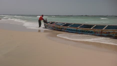 A-fisherman-working-in-his-ouboard-motor-at-the-shore-on-the-beach