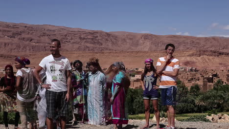 Touristen-Fotografieren-Mit-Dorfbewohnern-Und-Kamelen-In-Der-Marokkanischen-Wüste---Zeitraffer