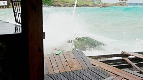 Local-wooden-fishing-boat-being-smashed-into-pieces-during-sudden-storm-with-rough-waves,-Caribbean
