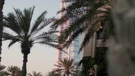 Reveal-Burj-Al-Arab-From-Behind-Palm-Trees,-Move-Left-and-Focus