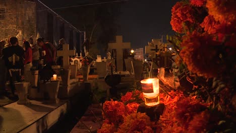 candle-on-fire-over-cempasuchitl-flowers-in-front-of-a-grave-in-a-traditional-cemetery-of-Mixquic-Mexico