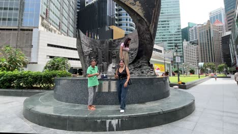 Tourists-take-photos-of-the-Progress-and-Advancement-Sculpture-in-Raffles-Place,-Singapore
