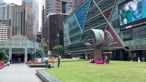 Tourists-and-locals-chill-out-at-an-outdoor-park-in-Raffles-Place,-Singapore