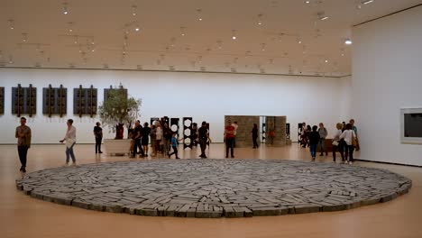 Bilbao-Circle-sculpture-by-Richard-Long-inside-the-Guggenheim-Museum-with-people-walking-around-it,-Wide-stable-shot