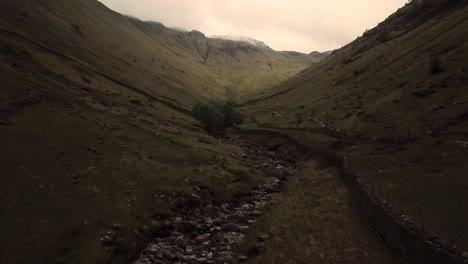 Drone-footage-over-a-green-valley-in-lake-district-park,-rock-formation-and-glacier-footprints