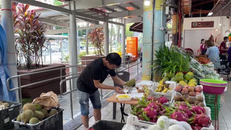 Obstverkäufer-Schneidet-Gekonnt-Mit-Einem-Messer-Durian-Fleisch,-Um-Es-In-Singapur-In-Eine-Einweg-Styroporbox-Zu-Verpacken