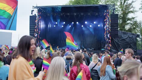 Oslo-Pride-2022-stage-with-glowing-lights-and-waving-rainbow-flags,-crowd-view