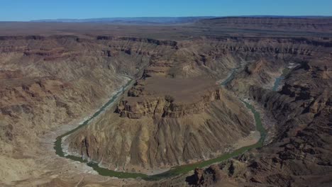 Drone-shot-of-the-Fish-River-Canyon-in-Namibia---drone-is-circling-around-a-hill-circumscribed-by-the-river