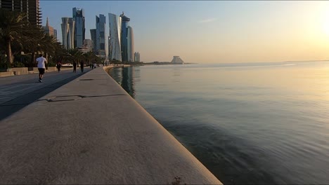 Seaside-pavement-with-Qatari-people-jogging-at-morning,-Doha-cityscape