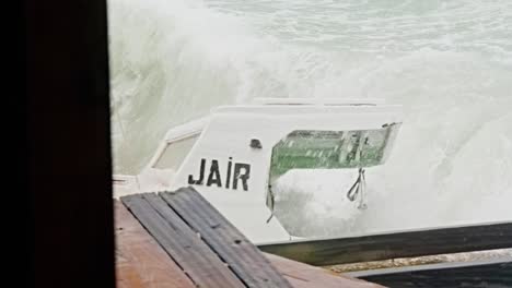 Close-up-of-local-wooden-fishing-boat-being-smashed-into-pieces-during-sudden-storm-with-rough-waves,-Caribbean