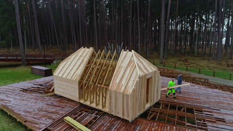 aerial-footage-of-a-wooden-plateau-and-house-under-construction-with-a-frame-with-trusses-in-a-forest