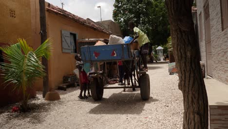 Three-kids-load-rubbish-onto-a-cart-pulled-by-a-donkey