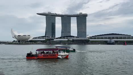 Touristenboote,-Die-Entlang-Des-Singapore-River-Kreuzen,-Mit-Blick-Auf-Die-Berühmten-Marina-Bay-Sands-Und-Das-Art-Science-Museum-In-Singapur