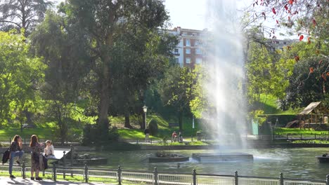Main-pond-with-tall-waterspout-fountains-in-Doña-Casilda-Park-with-people-enjoying-day,-Locked-shot