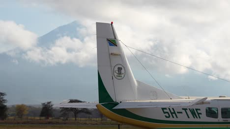 Tail-section-of-208B-Grand-Caravan-Cessna-commuter-plane-with-Mount-Kilimanjaro-behind-clouds,-Medium-shot