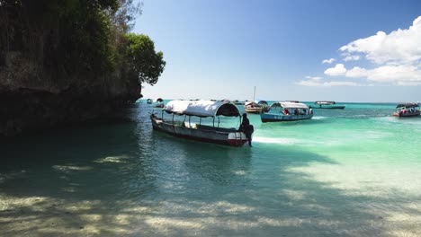 Tour-boat-arriving-to-pick-up-tourists-and-workers-on-shallow-beach,-Locked-wide-shot