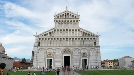 Slow-gimbal-shot-of-Cathedral-of-Pisa-facade,-tourists-passing-by,-Pisa,-Italy