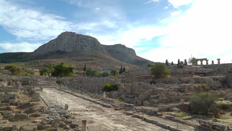 Panoramic-View-of-Lechaion-Road-in-the-City-of-Ancient-Corinth-with-Acrocorinth-Mountain-in-Background-on-Sunny-Day