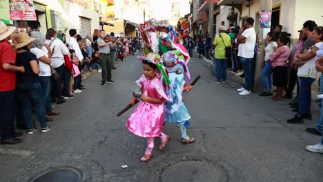 Niños-Y-Adultos-Mexicanos-Vestidos-Con-Coloridos-Trajes-Tradicionales-Mientras-Bailan-En-La-Calle-En-El-Desfile-De-Danza-Ancestral-En-Tuxpan,-Jalisco,-México