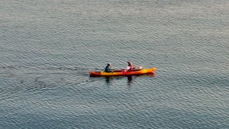 Close-up-aerial-drone-view-of-young-couple-having-fun-in-a-sea-kayak-paddling-in-a-bay-near-seattle-washington-right-after-sunrise-in-the-morning