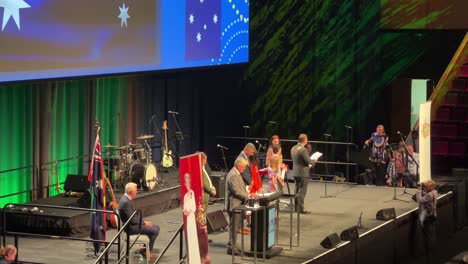 Supersized-grand-ceremony-in-Brisbane-due-to-pandemic,-selected-representatives-receiving-their-citizenship-certificate-from-Lord-Mayor-Adrian-Schrinner-on-stage-at-convention-and-exhibition-centre